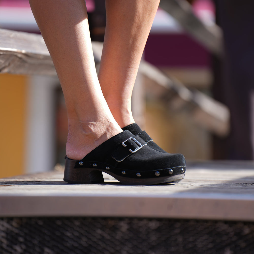Person wearing a black shoe with a strap on a blurred background