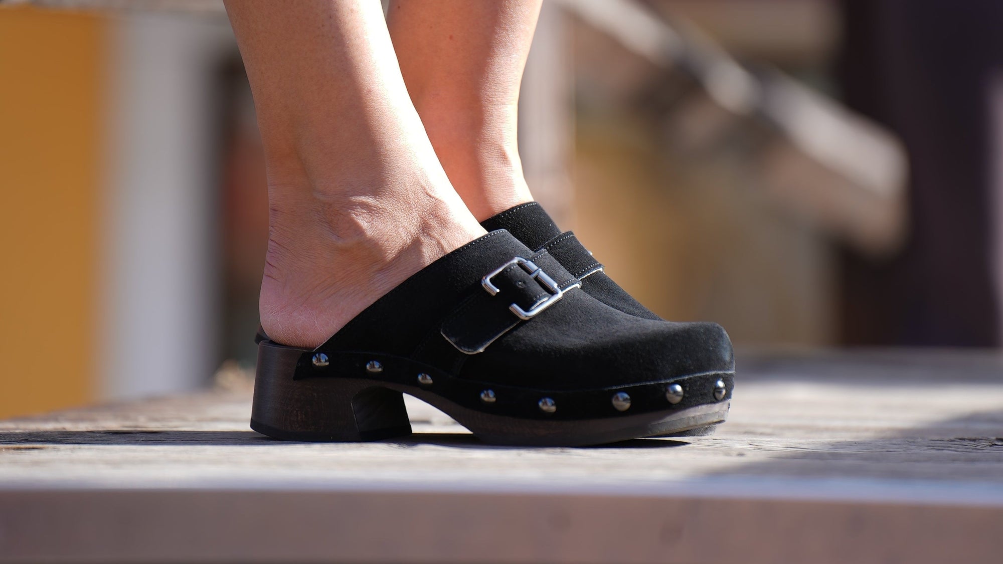 Person wearing a black shoe with a strap on a blurred background